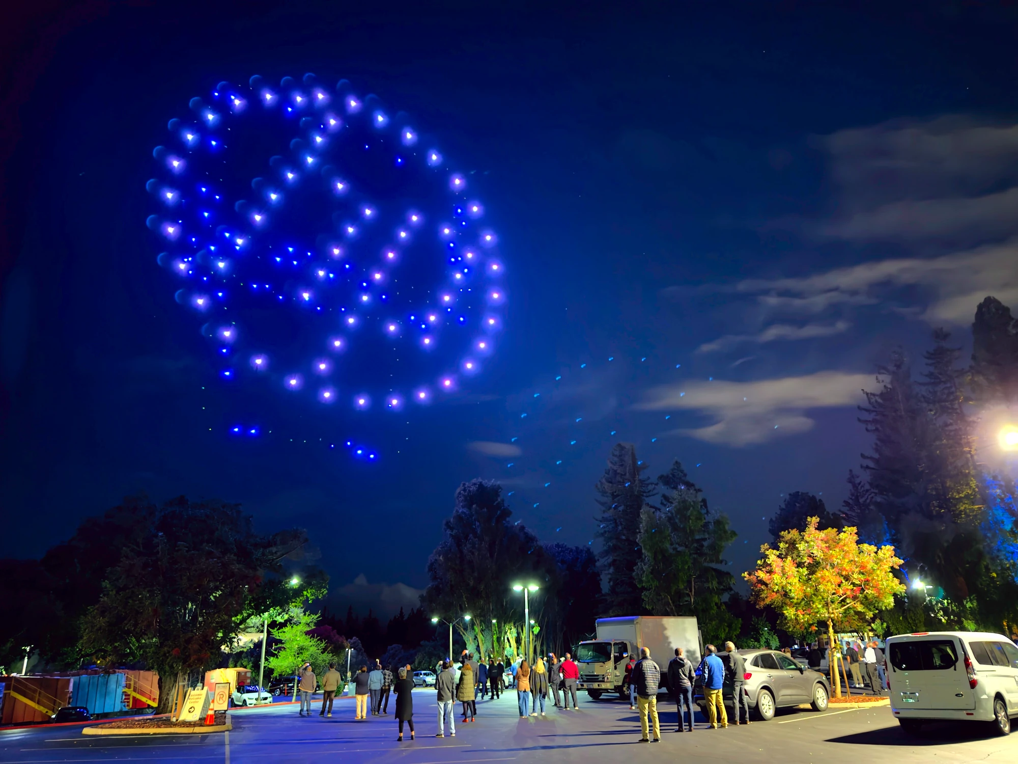 Drone light show forming an abstract globe above the crowd at an evening tour stop