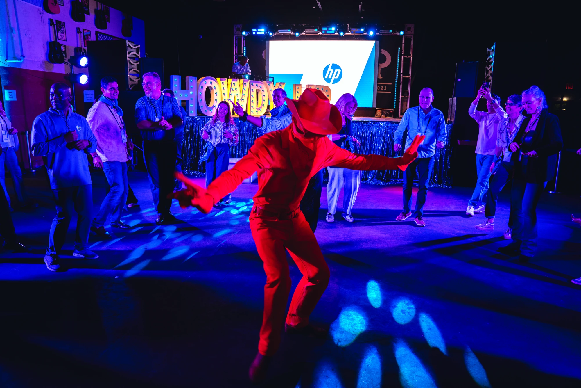 Red-suited performer working the crowd beneath the Howdy marquee at the Neon Cowboy offsite