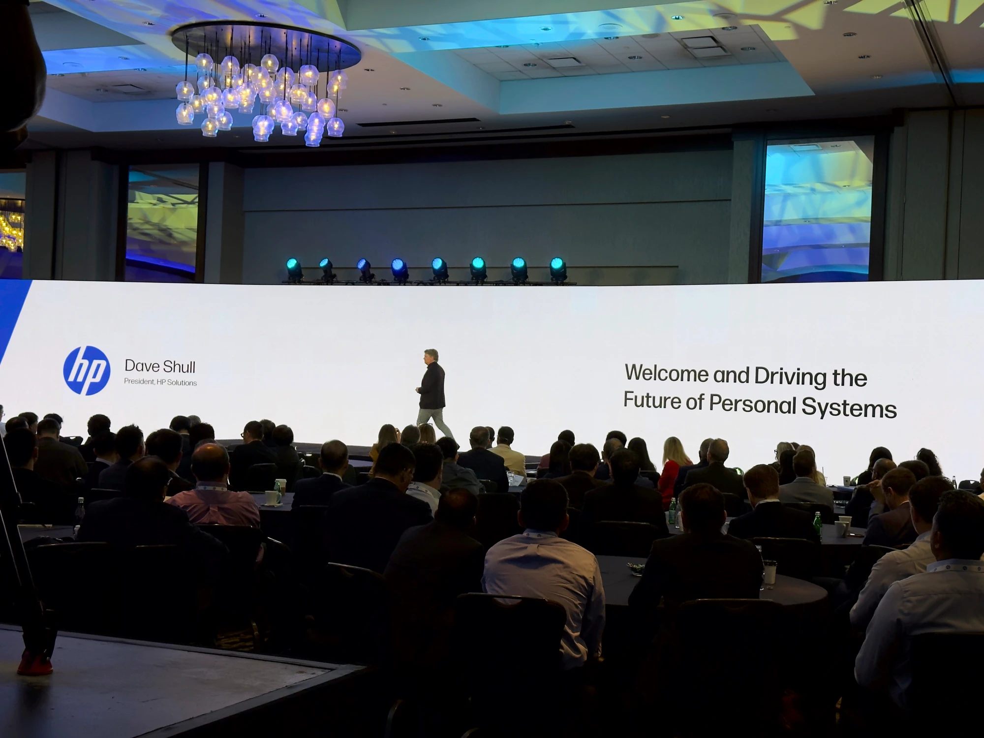 Speaker crossing a full-width LED wall at a corporate summit.