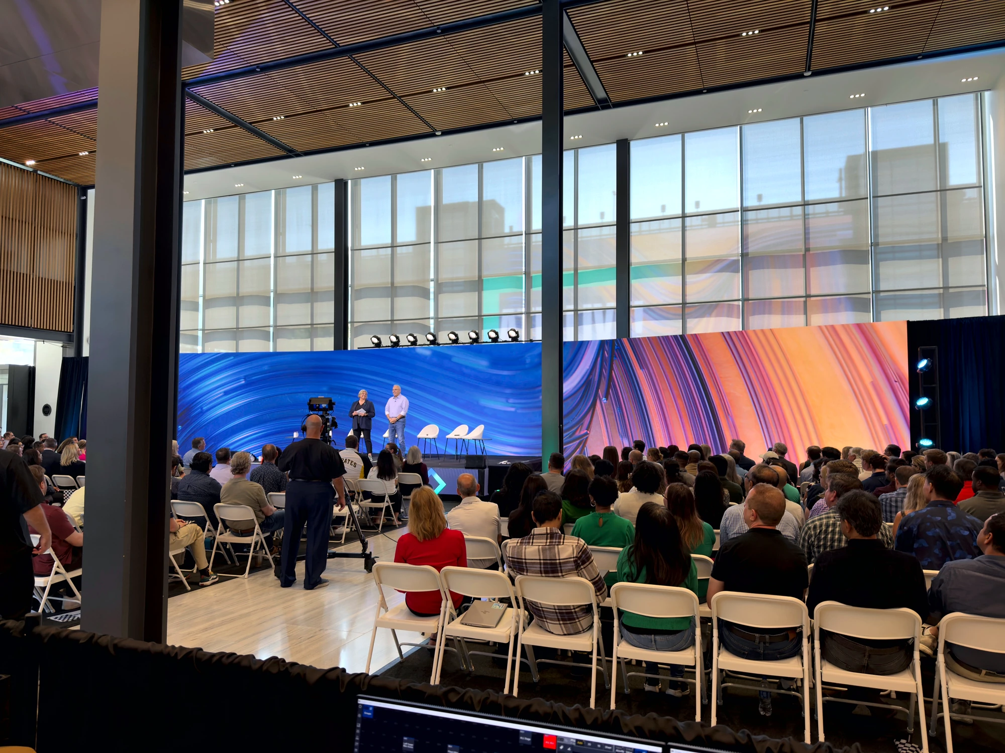The live audience watching a panel discussion against the sweeping LED wall