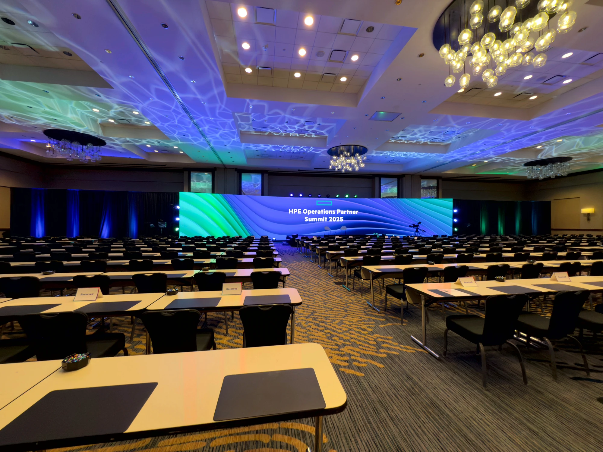 Wide LED wall filling the front of a corporate general-session room.