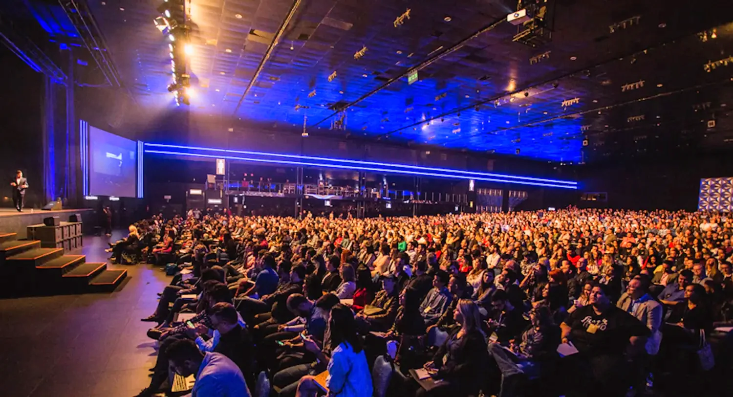 Packed general session during a hybrid keynote broadcast in a convention ballroom.