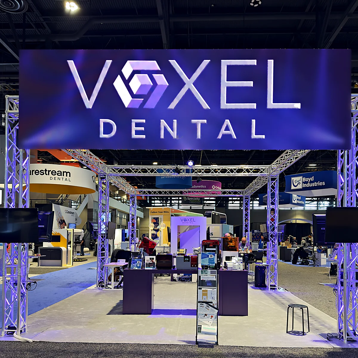 Voxel Dental’s trade-show booth: the Voxel Dental logo on an LED wall over lit truss